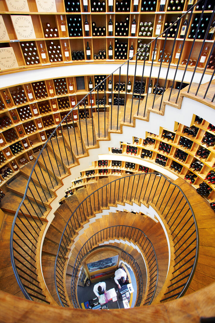 Spiral staircase with wine bottles kept on rack in L'Intendant wine shop, Bordeaux, France