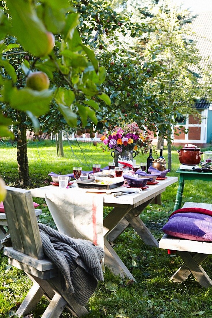 A table laid in a garden under apple trees