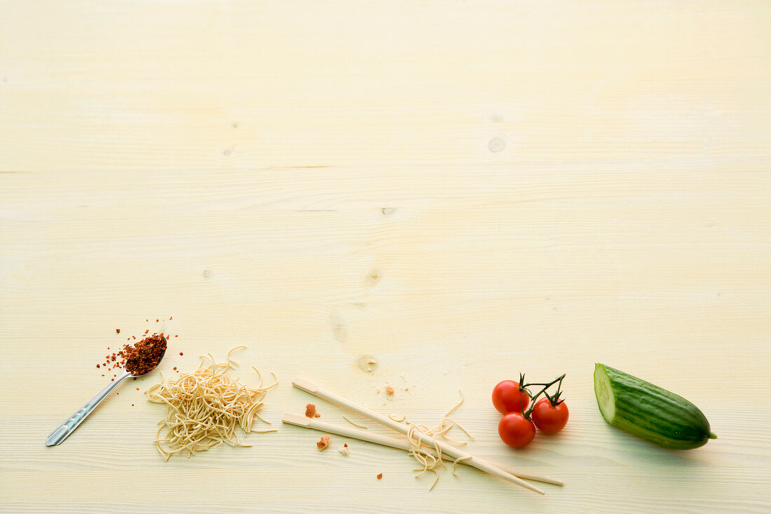 Zucchini, cherry tomatoes, chopsticks, noodles and spices on yellow background