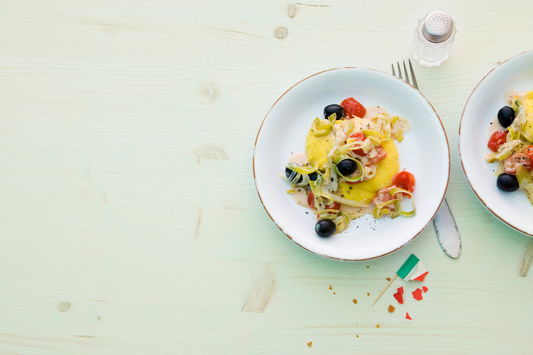 Saffron polenta with tomatoes and leeks on plate