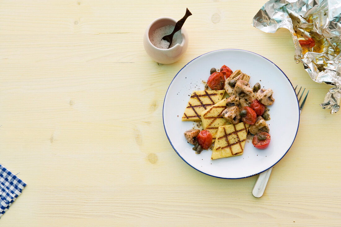 Grilled polenta with mushrooms and cherry tomatoes on plate