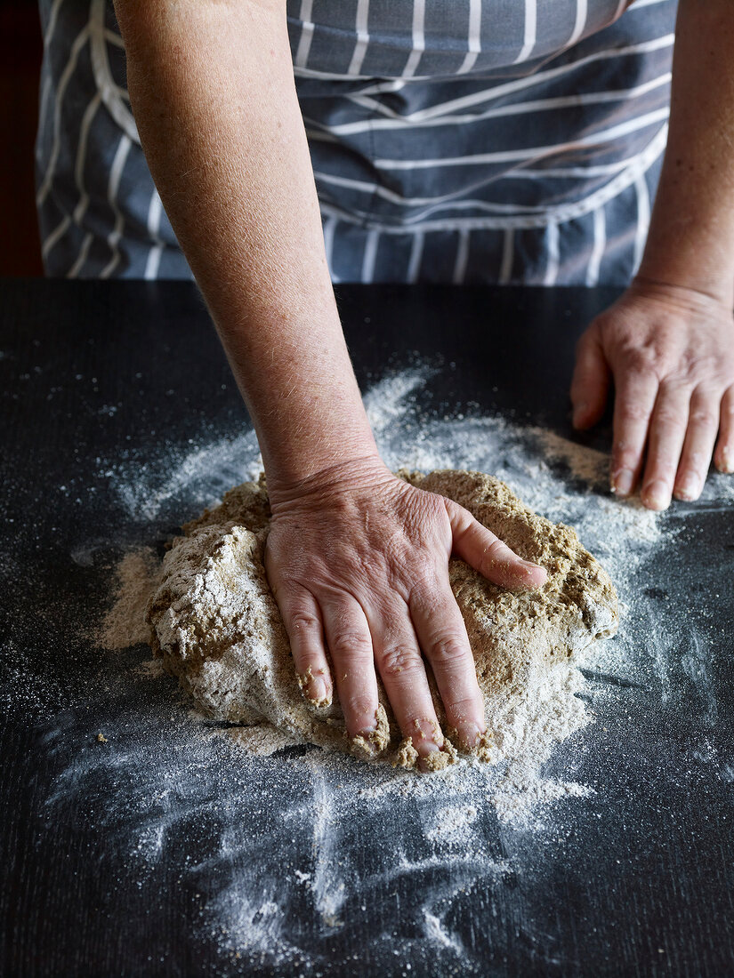 Close-up of hand kneading dough for preparing sourdough bread