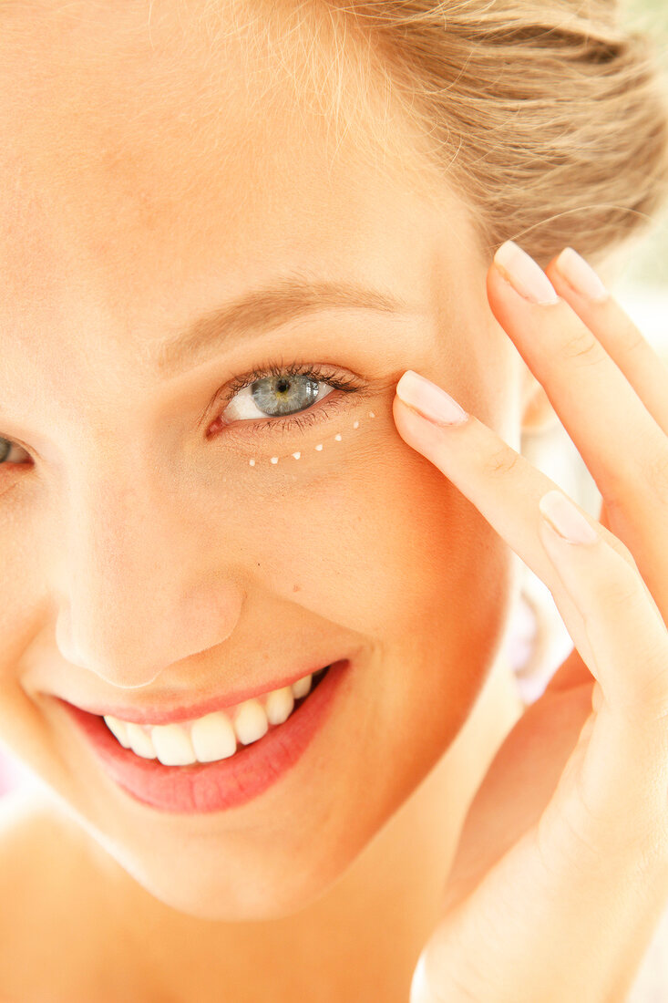 Woman dabs on eye cream (close-up)
