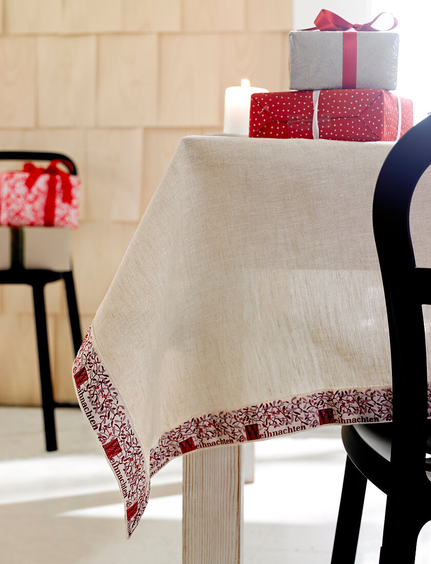 Linen tablecloth on table with Christmas gifts on top