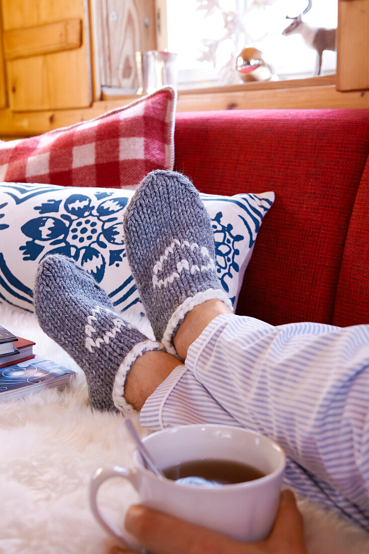 Woman's legs wearing knitted house slipper socks with heart motif