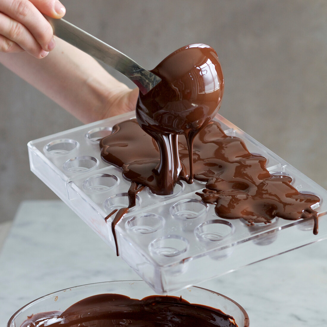 Melted chocolate being poured in hollow cast with ladle, step 1