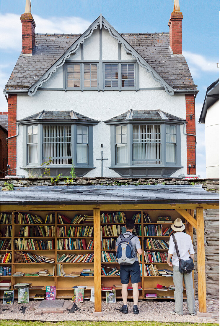Men at outside bookstore in Hay-on-Wye village, Powys, Wales, UK