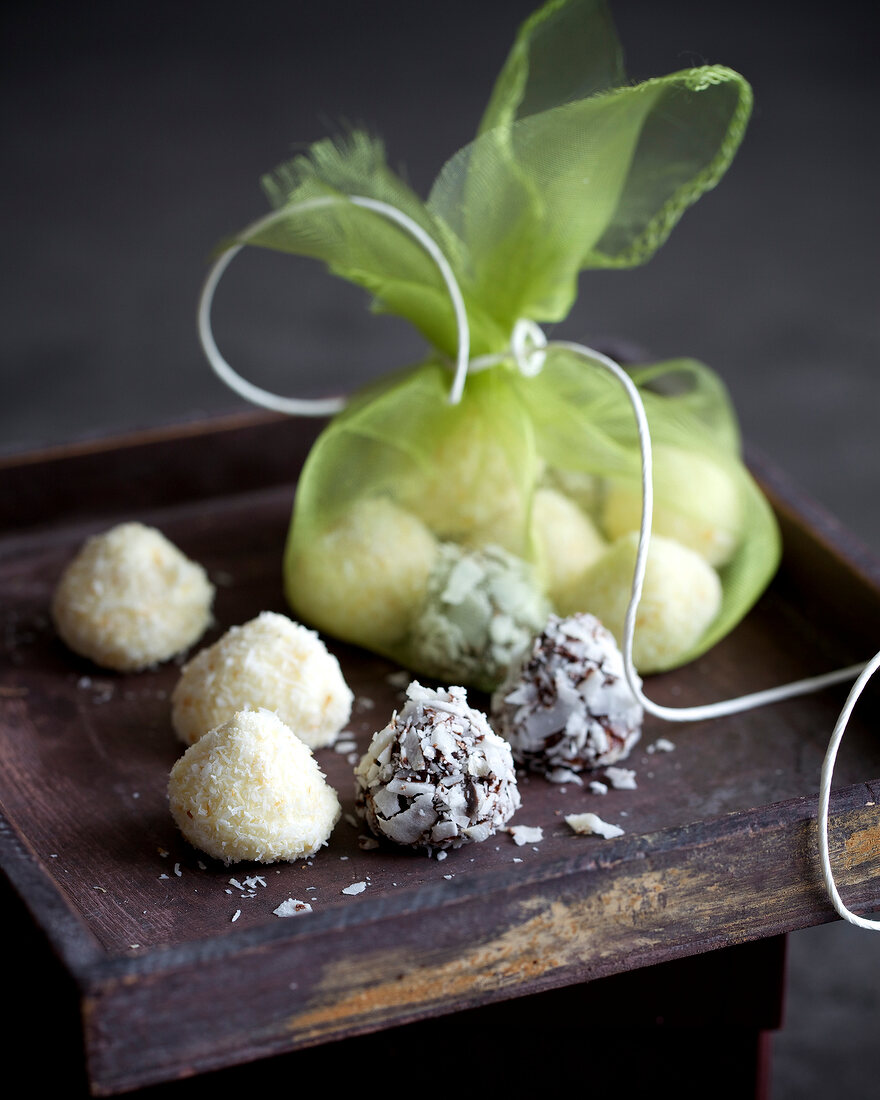 White coconut truffles in green bag and on wooden surface