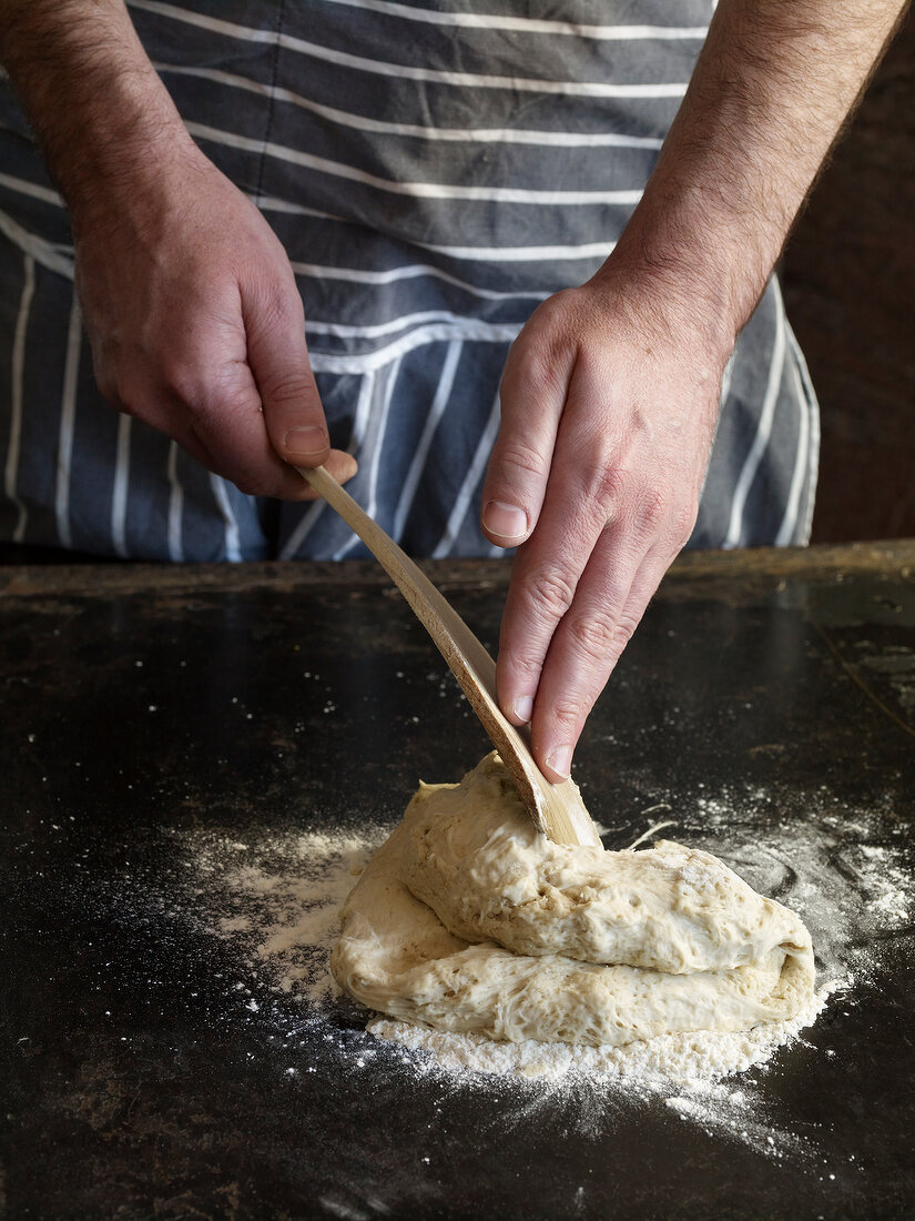 Close-up of hand folding dough with dough scraper