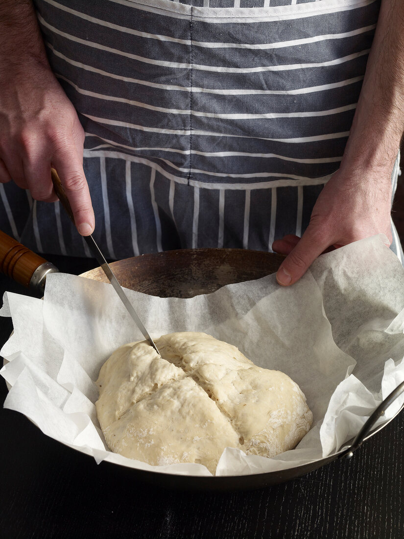 Close-up of hand cutting dough with knife
