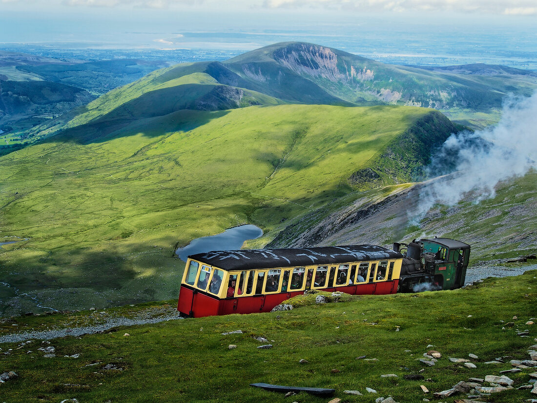 People travelling in train at Snowdonian National Park with mountain ranges, Wales, UK