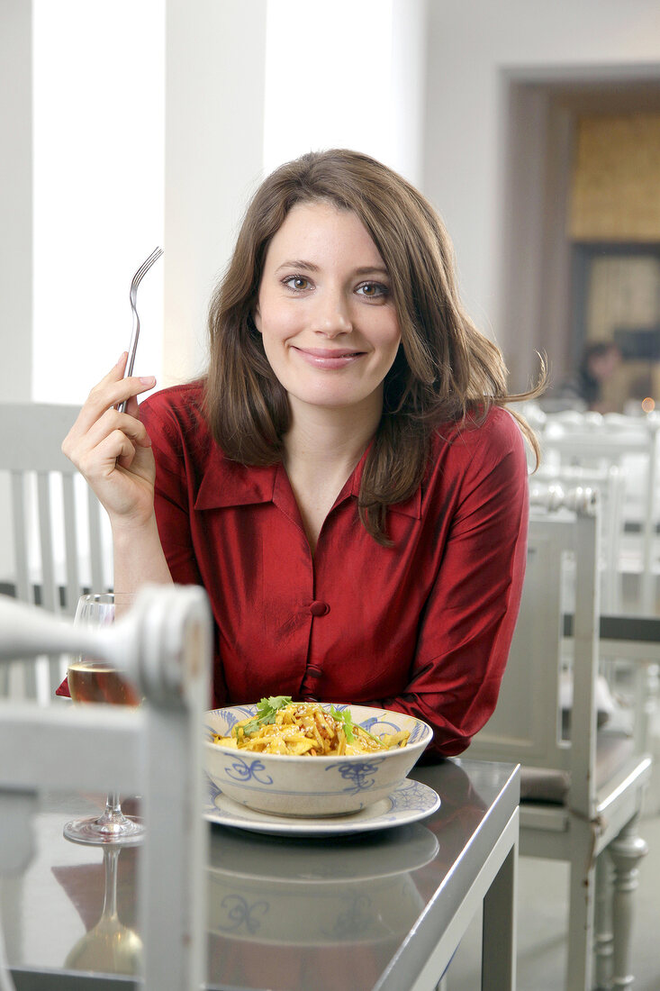 Frau mit langen braunen Haaren und roter Bluse im Restaurant