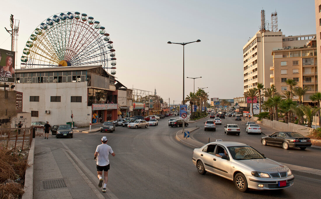 Cars and people on street with ferries wheel in background at Luna park, Beirut, Lebanon