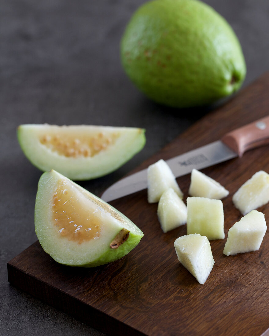 Guava being cut into small pieces with knife for preparing guava and lime truffle, step 1