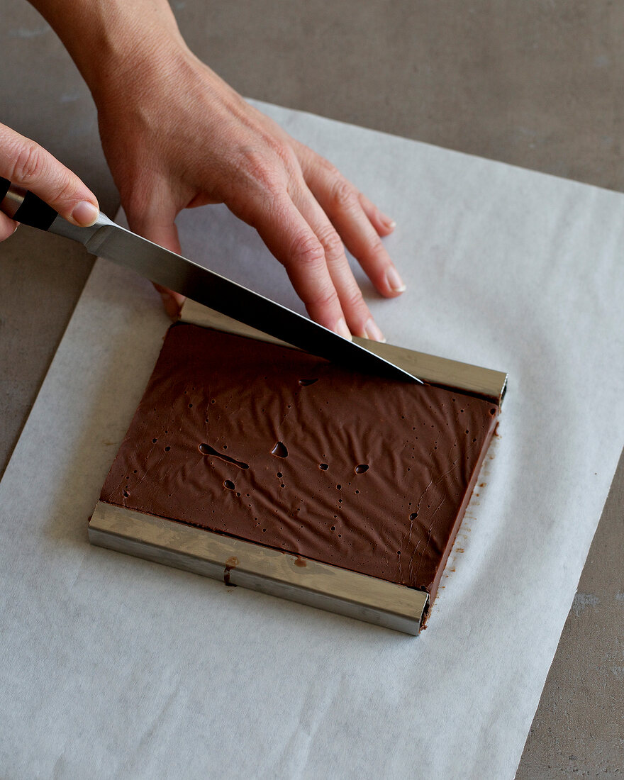 Close-up of hand removing chocolate from mould with knife, step 2