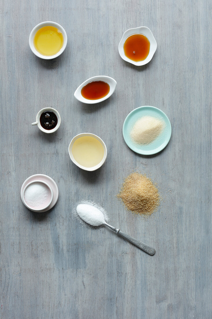 Different types of uncooked sweeteners in bowls and plates