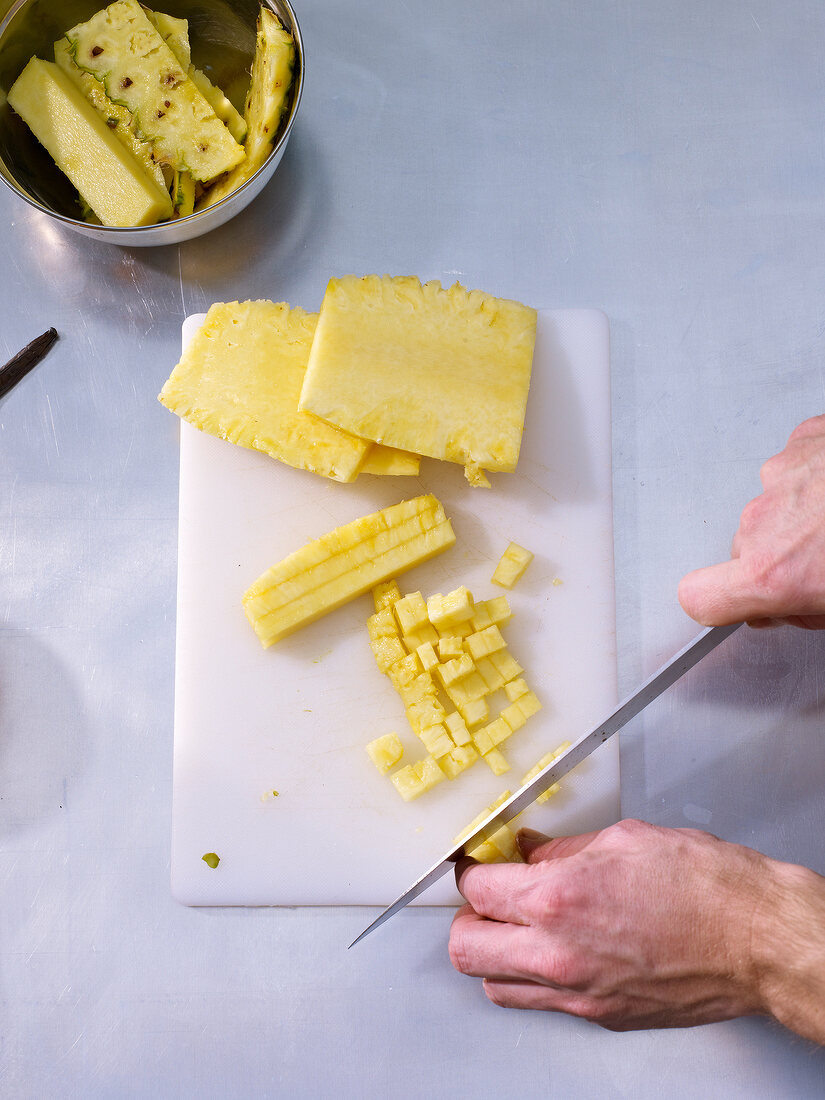 Chopping pineapples in cubes on cutting board