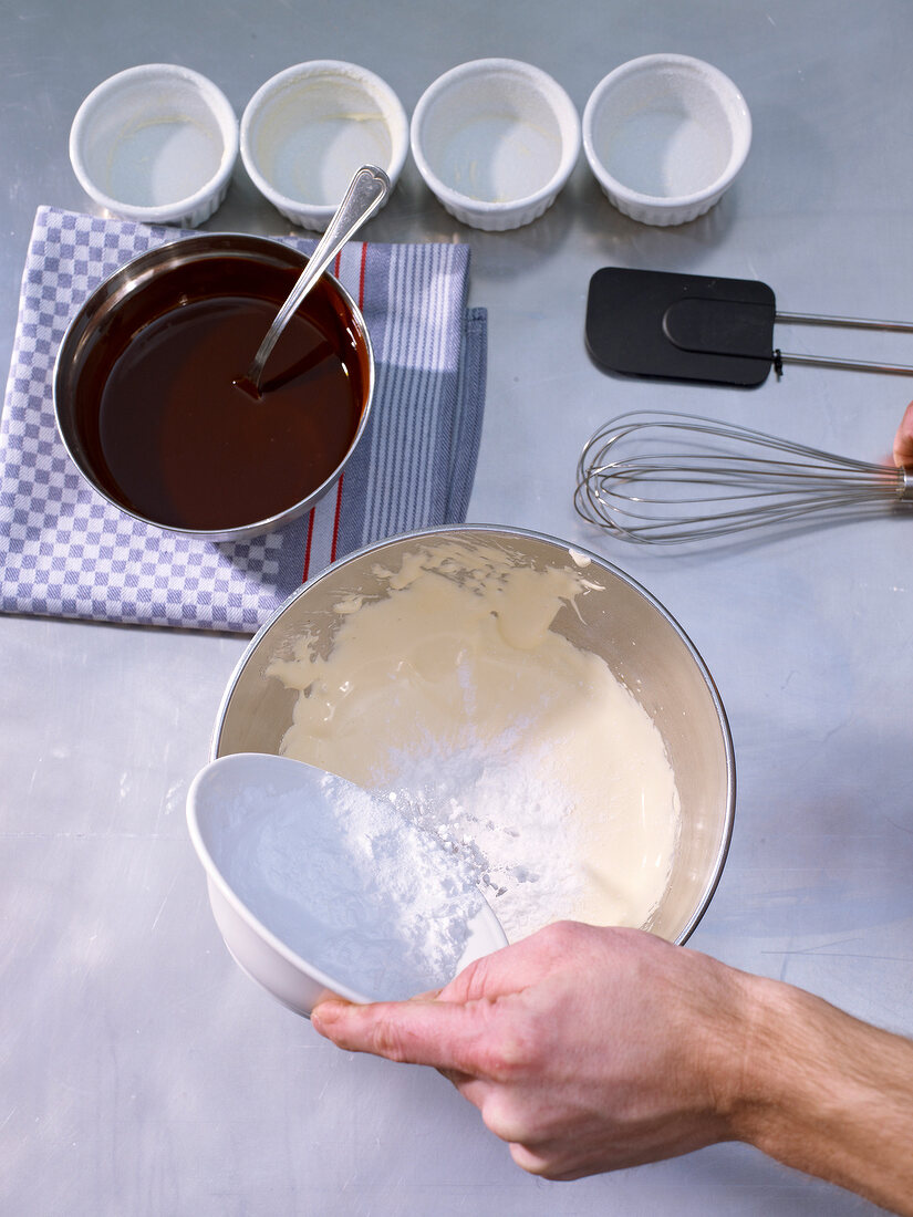 Adding powdered sugar to bowl of beaten egg yolks