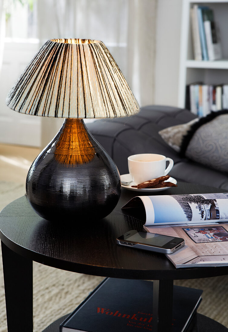 Small illuminated table lamp and coffee cup on black table