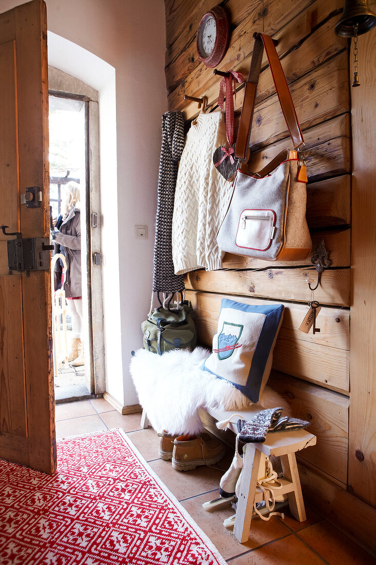 Entrance of cloakroom with clothing, bags, stool, cushion and carpet
