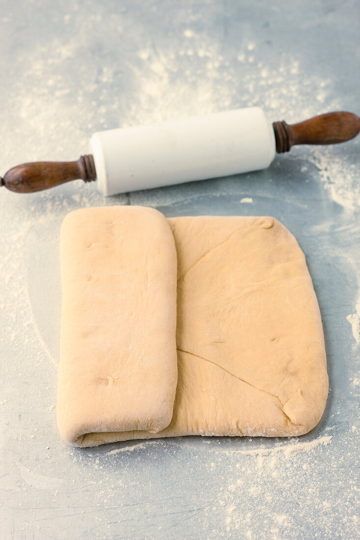 Rolled dough with butter being folded while preparing pastry, step 3
