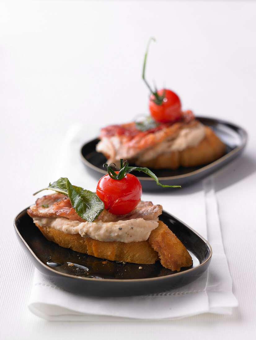 Saltimbocca crostini with puree of white beans in serving dish