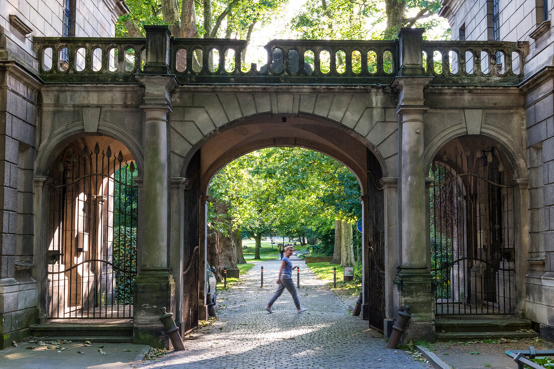 Woman passing at gatehouse in old garden, Hannover, Germany