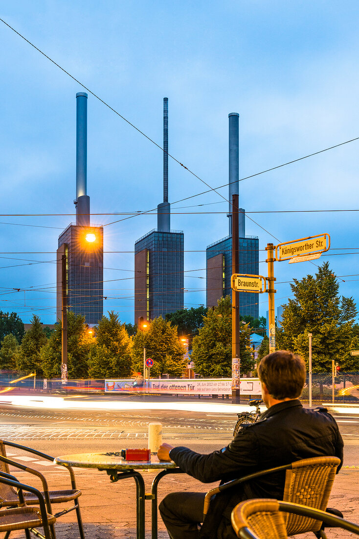 Man sitting outside cafe and in front of Thermal power station, Hannover, Germany