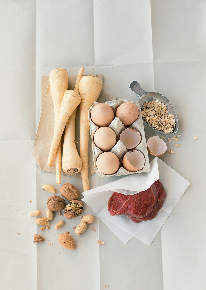 Oatmeal, eggs, nuts, meat and parsnips on white background