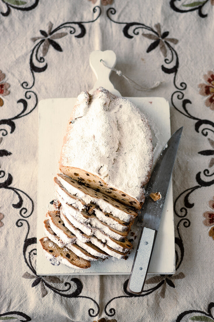 Pieces of Christmas stollen with knife on chopping board
