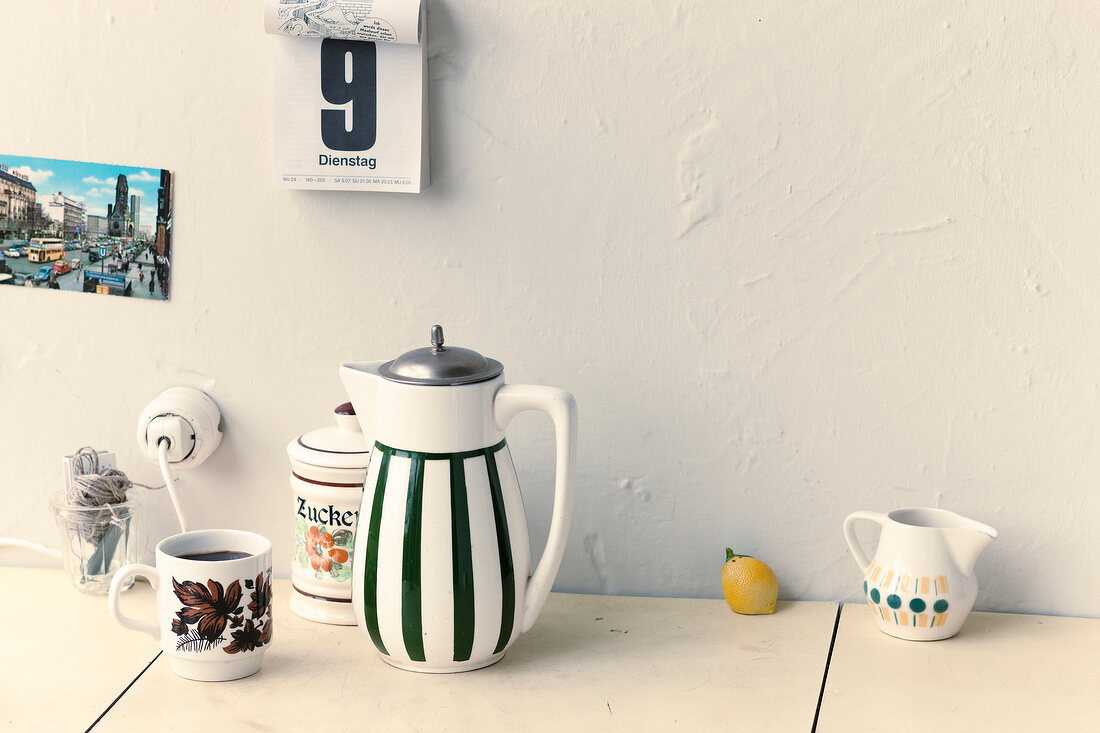 Cup of coffee, jar and lemon on table and calendar on wall