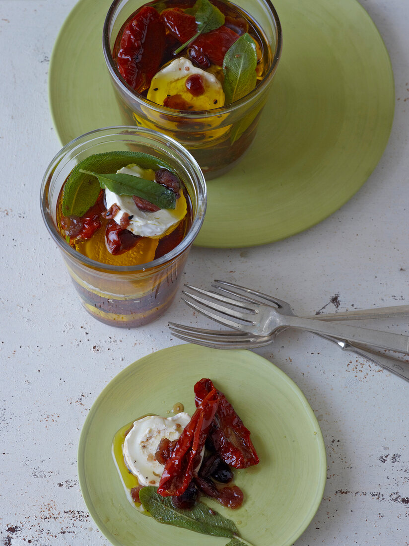 Dried tomatoes with goat cheese and olive oil in glasses and plate