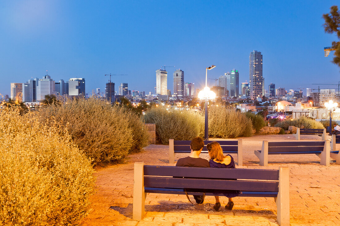 Rear view of couple sitting on bench at dusk, Neve Tzedek, Tel Aviv, Israel