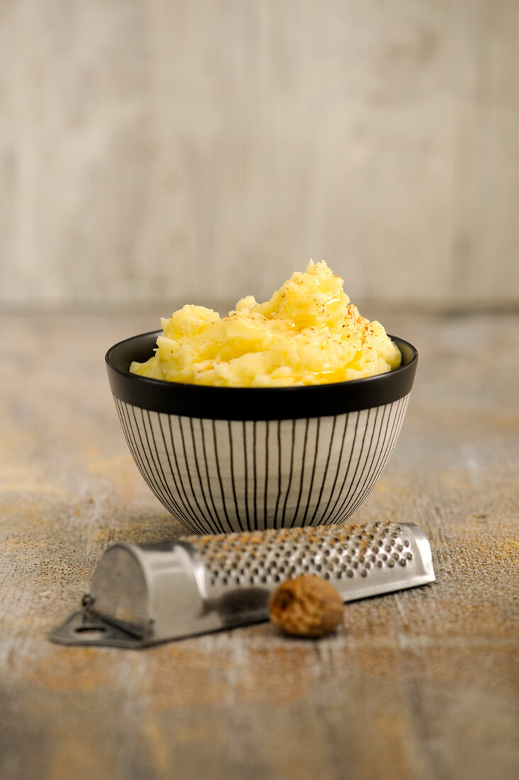 Mashed potatoes in bowl with grater at side