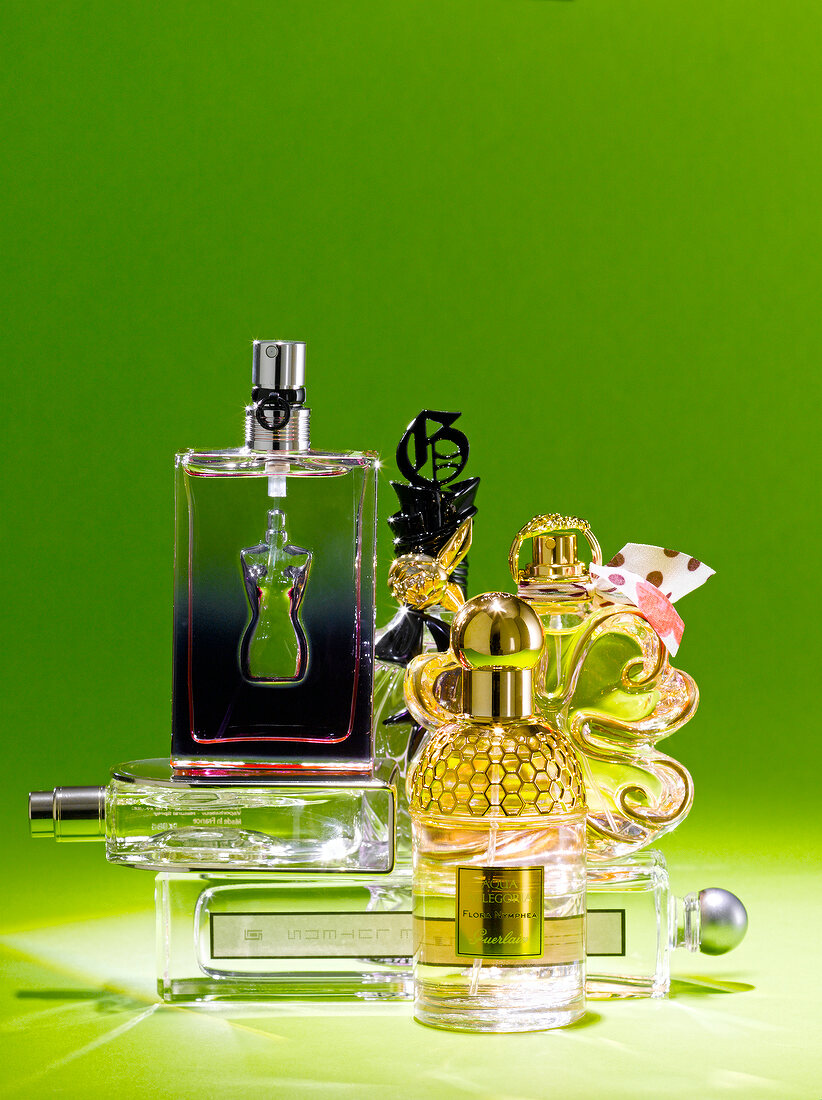 Various types of perfume bottles in Paris style against green background