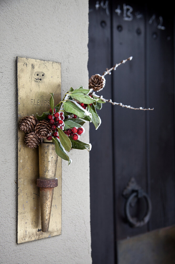 Entrance of door decorated with berries and leaves in cone