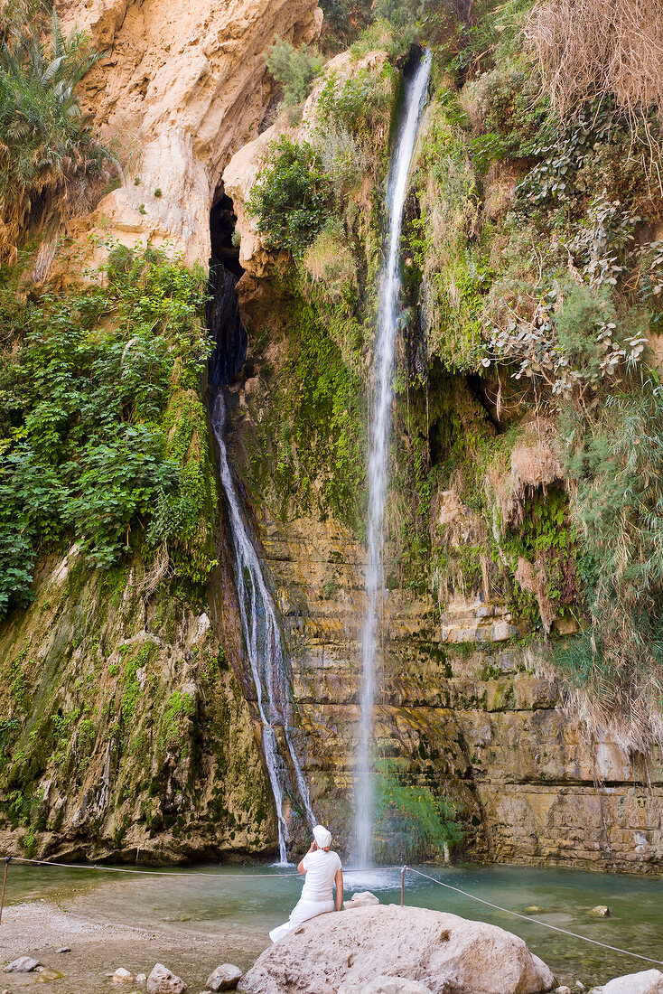 Tourist standing in front of waterfall, Wadi David, Ein Gedi National Park, Israel,