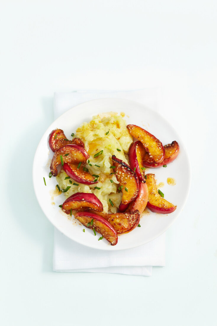 Slices of apples with parsnip and peppers mash on plate