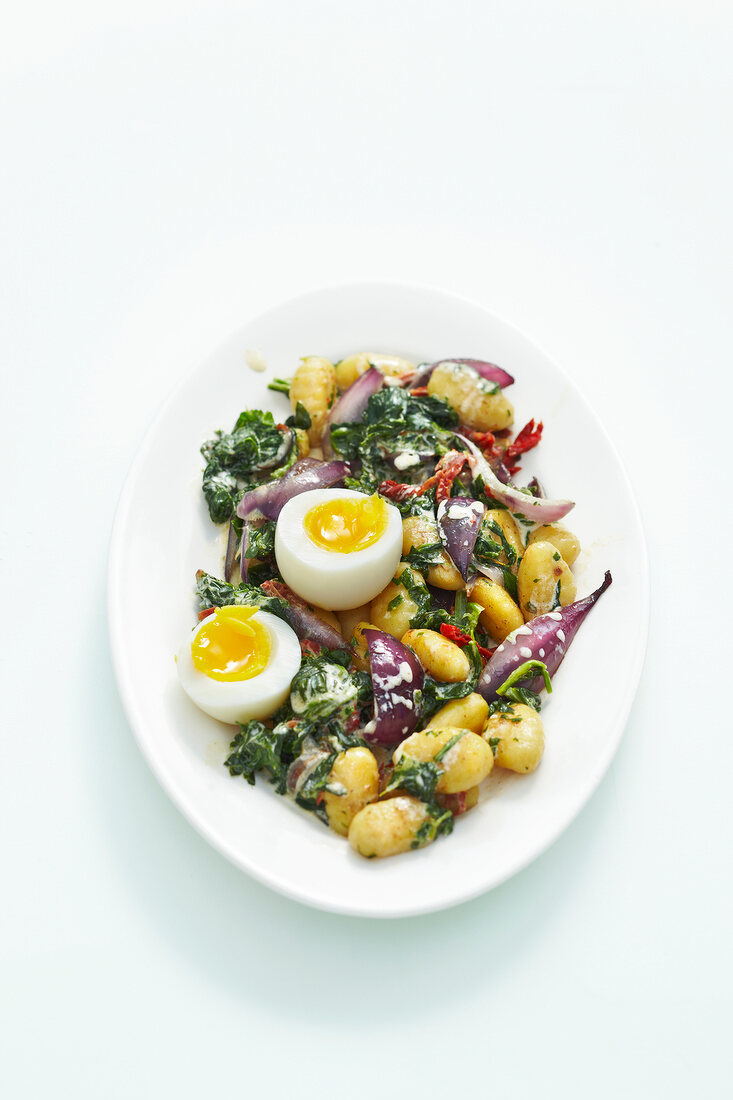Spinach with eggs, onion and gnocchi in serving dish