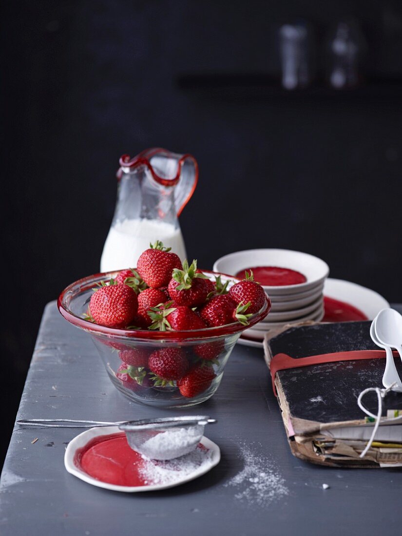 Stillleben mit Erdbeeren in Glasschale neben altem Notizbuch
