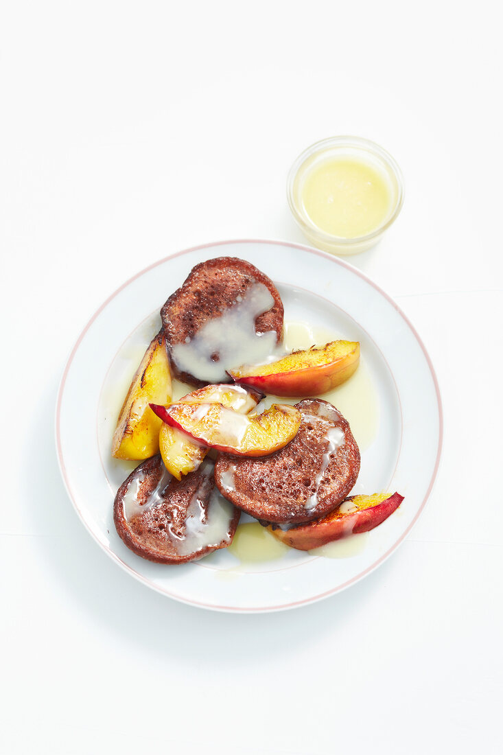 Chocolate pancakes with slices of peaches on plate