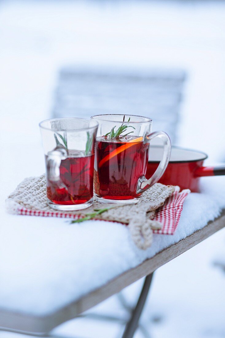Glasses of mulled wine garnished with orange slice in the snow