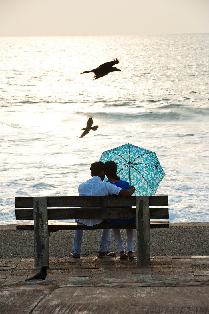 Rear view of couple sitting on bench at dusk, Colombo, Sri Lanka