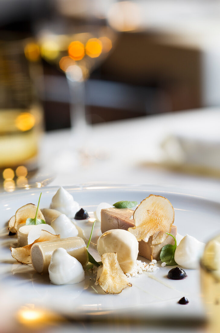 Goose liver terrine with popcorn, Jerusalem artichokes and elderberries on plate