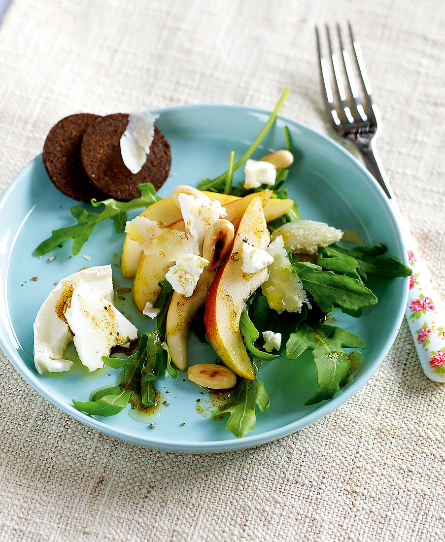 Pumpernickel pear salad with goat cheese on blue serving dish