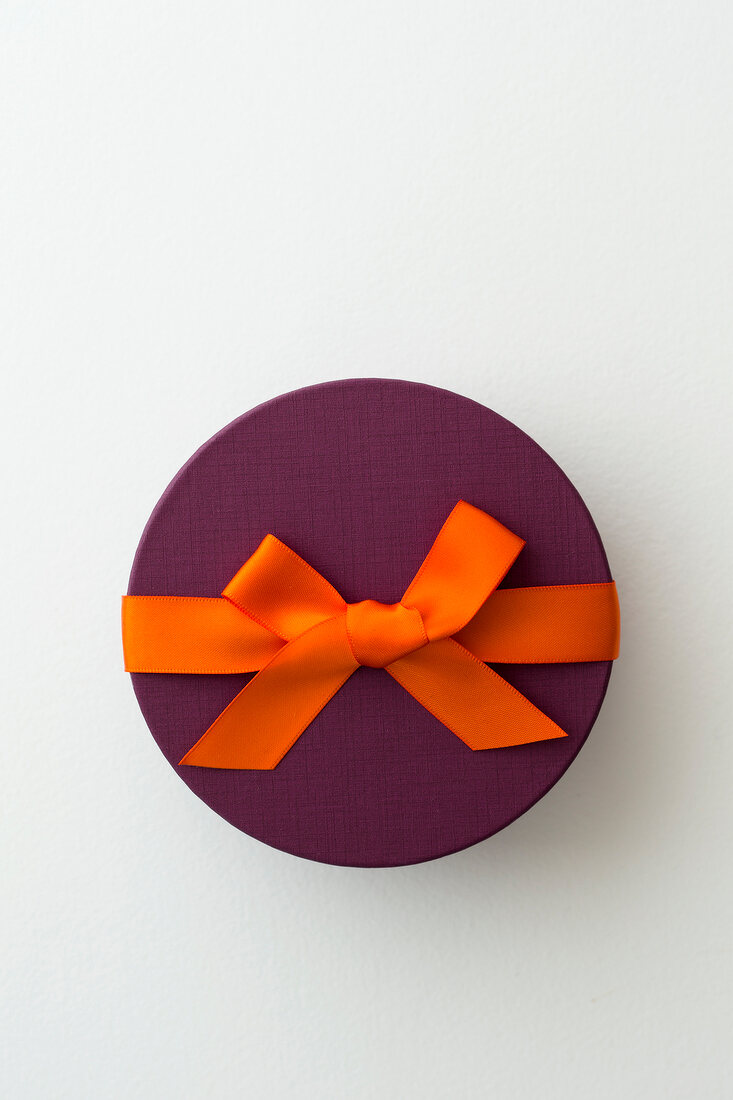 Box of chocolates with orange bow on white background