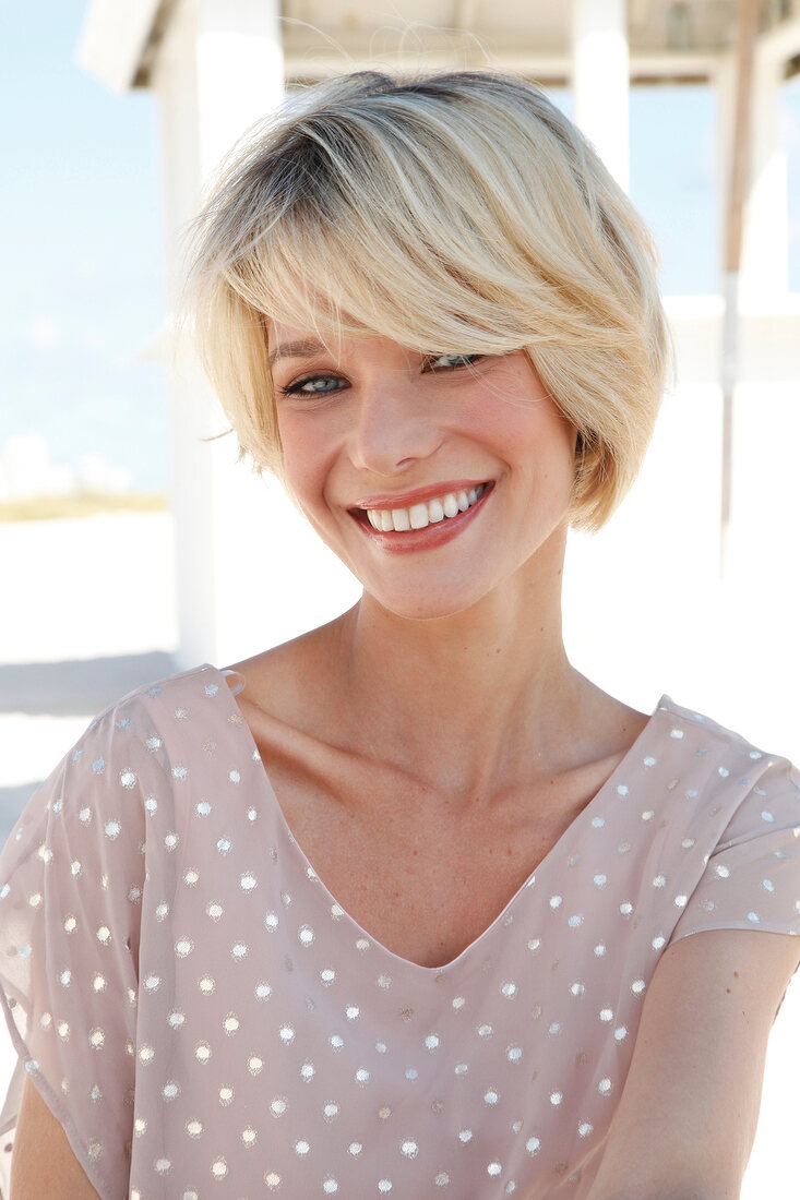 Portrait of happy blonde woman with short hair wearing polka dots dress, smiling