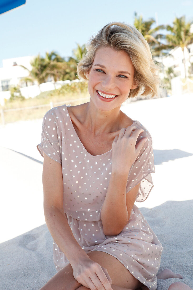 Portrait of happy blonde woman with short hair wearing polka dots dress, smiling