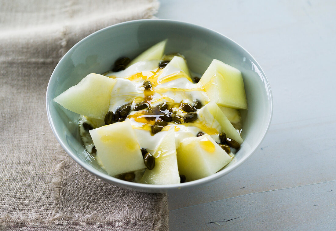 Yogurt with melon, pistachio and honey in bowl