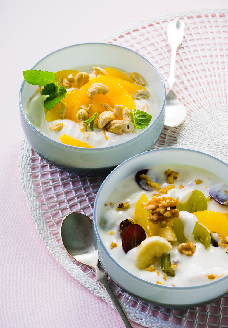 Orange yogurt with cashew nuts and fruits salad in serving bowls